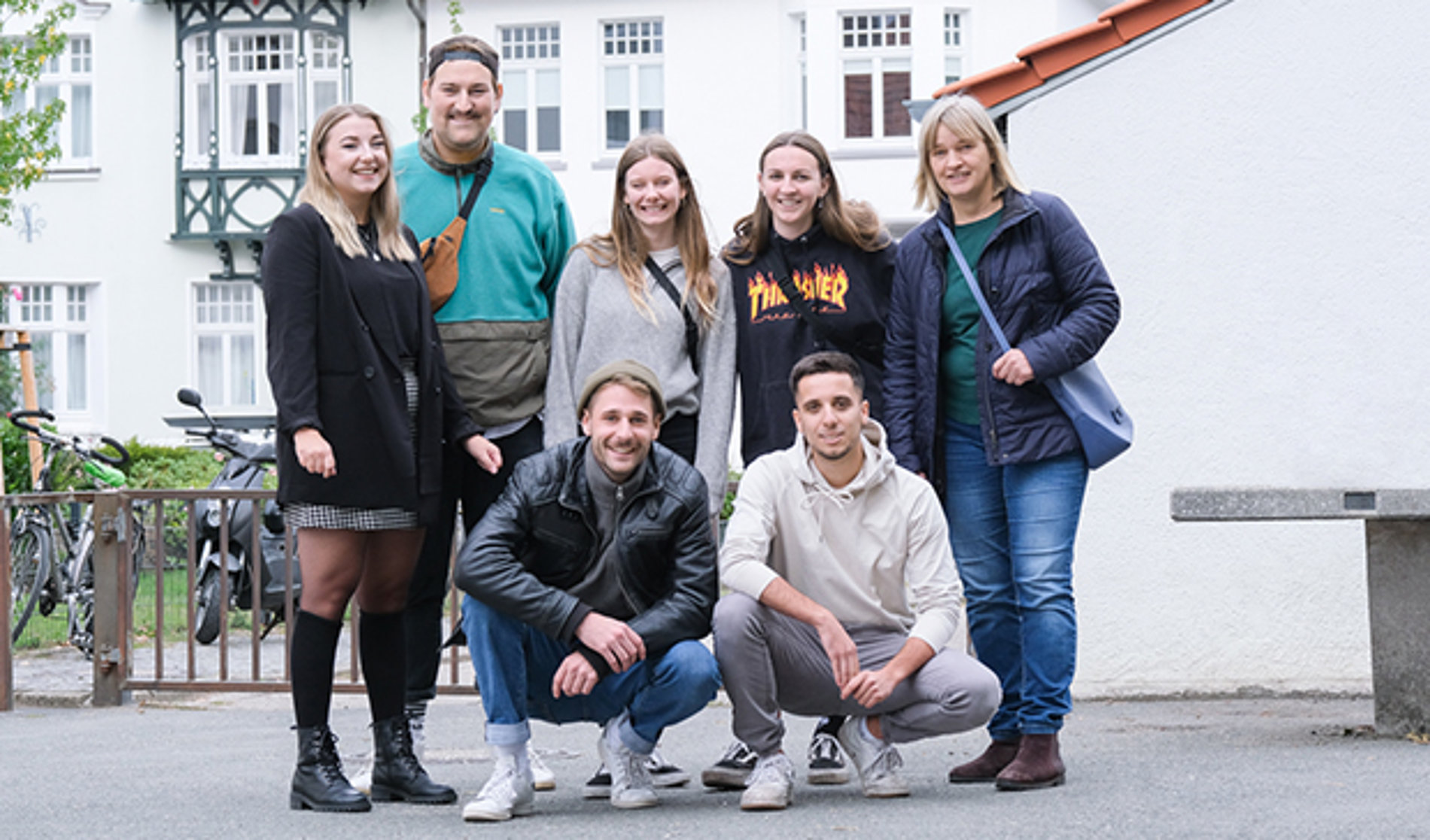 Ein Gruppenbild von sieben jungen Erwachsenen, die alle in die Kamera lächeln.