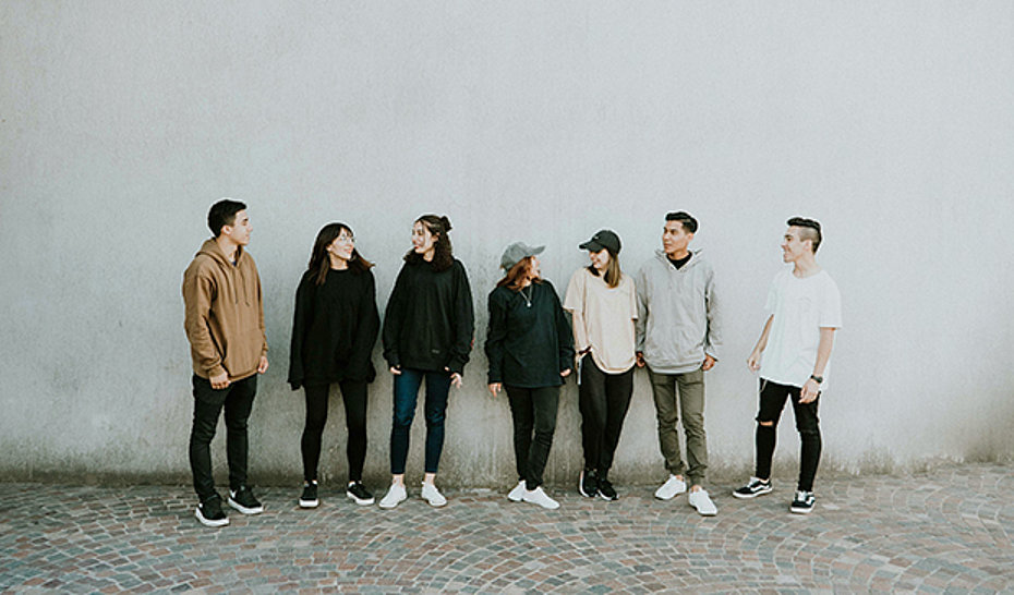 Sieben Jugendliche stehend vor einer weißen Wand.